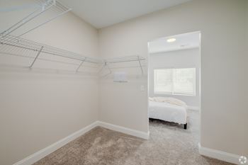 A bedroom with a bed, a window with blinds, and a closet with hanging rods.